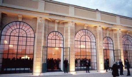 La Orangerie de Viena en un evento, vista desde el exterior, en el interior el público, delante algunas personas estirando las piernas