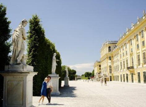 ウィーン・シェーンブルン宮殿 - 観光スポット ウィーンの観光スポット、シェーンブルン宮殿。右側に宮殿、左側に庭園で写真をとっている2人の観光客が見えます